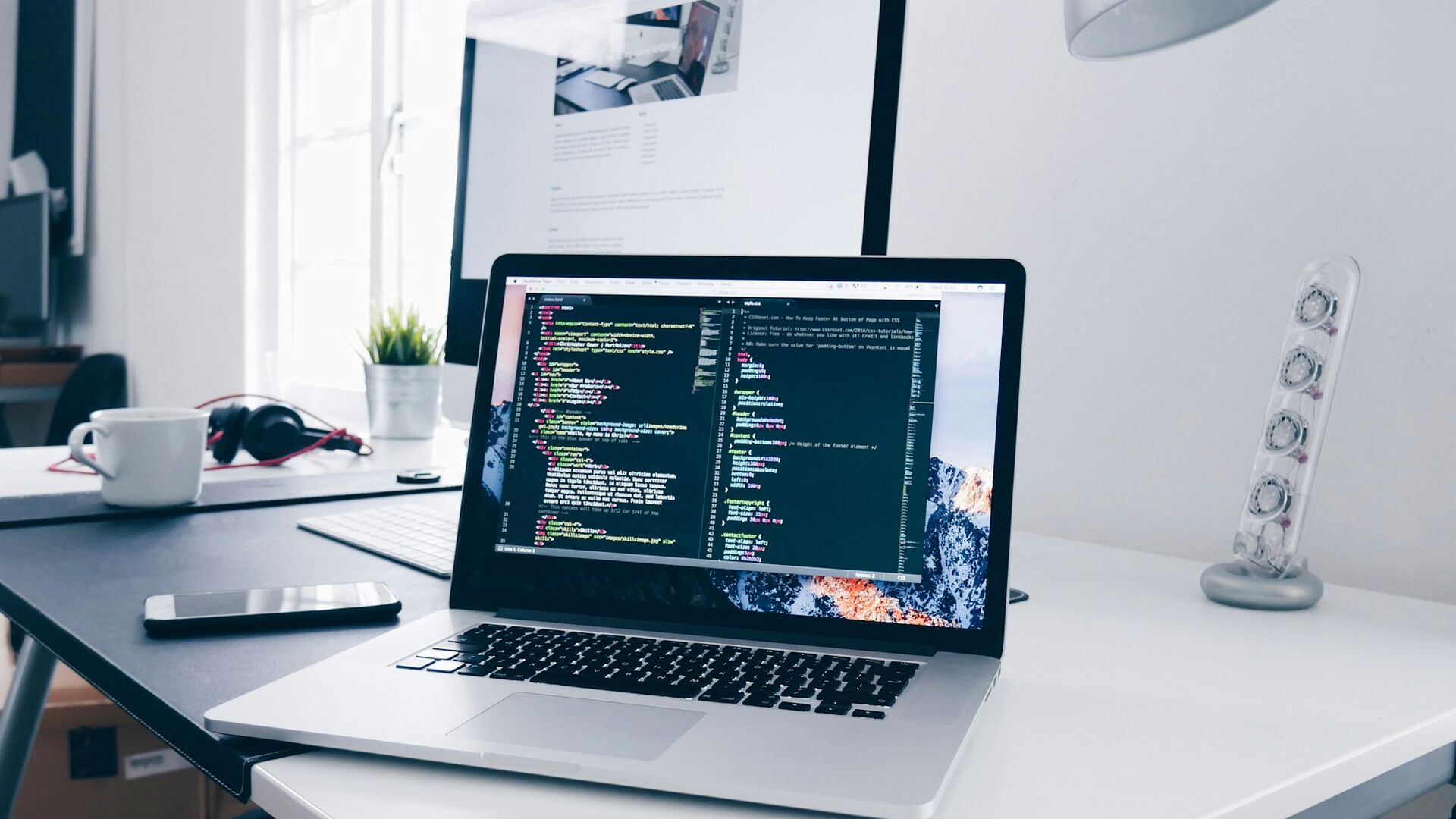 A developer's MacBook Pro showing source code on a bright desk